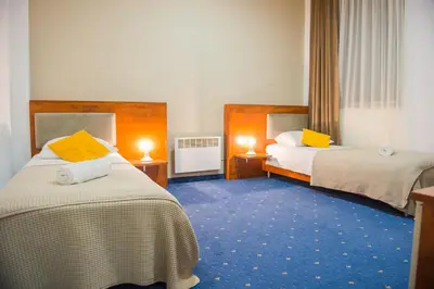 a hotel room with two beds with yellow pillows at Hotel CITY in Prnjavor