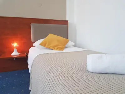 a bedroom with a bed with a yellow pillow on it at Hotel CITY in Prnjavor
