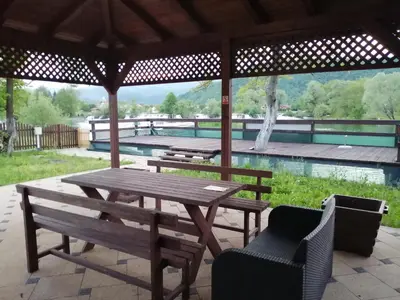 a picnic table and chairs under a pavilion with a pool at Villa Al Nemah in Bihać