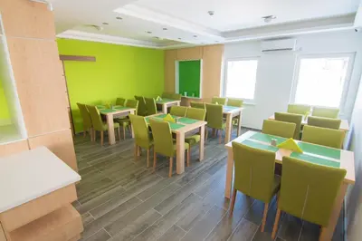 a dining room with green walls and tables and chairs at Laurus Motel Airport Tuzla in Živinice
