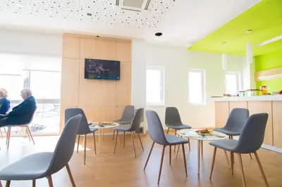 a waiting room with chairs and tables and a person at Laurus Motel Airport Tuzla in Živinice