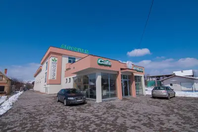 a building with two cars parked in front of it at Laurus Motel Airport Tuzla in Živinice
