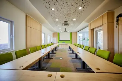 a row of desks in a room with green chairs at Laurus Motel Airport Tuzla in Živinice