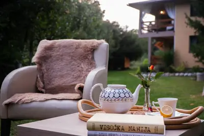 a table with a tea pot and a book and a chair at Eden Visoko in Visoko