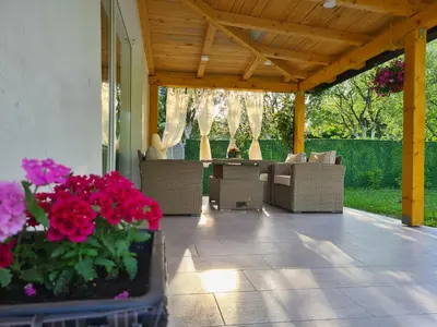 a patio with chairs and flowers on a porch at Orhidea in Bihać