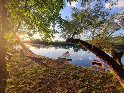 a hammock hanging from a tree next to a lake at Orhidea in Bihać