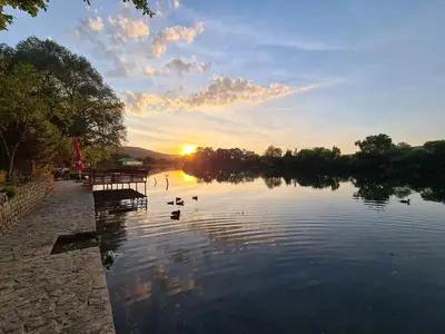 a group of ducks swimming in a lake at sunset at Orhidea in Bihać