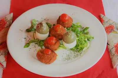 a plate of food with meatballs and salad on a table at Ski Rostovo - Hotel Rostovo & Ethno Village in Čardaci