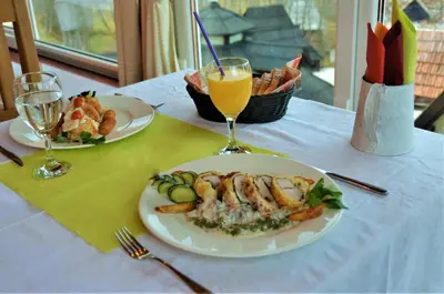 a table with two plates of food and a glass of orange juice at Ski Rostovo - Hotel Rostovo & Ethno Village in Čardaci