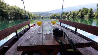a wooden table with two glasses of wine on a boat at Amal Grand Villa in Bihać