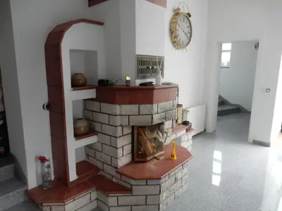 a brick fireplace in a living room with a clock at Luxeriöse Villa mit Bergblick in Donji Ljenobud