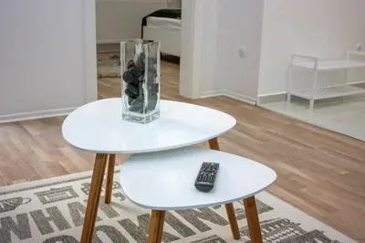 two white tables with a glass vase and a remote control at Villa Onix in Bihać