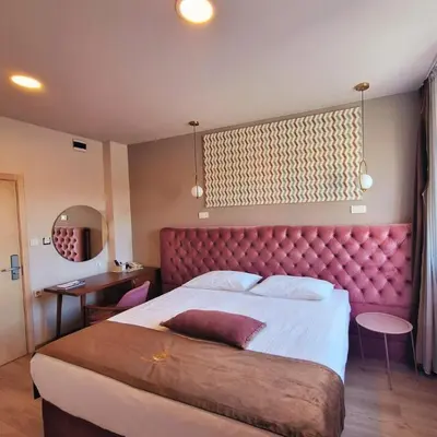 a bedroom with a large bed with a red headboard at Boutique Hotel St Georgije in Banja Luka