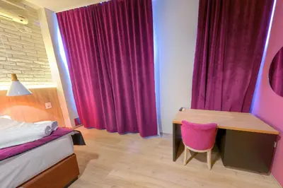 a bedroom with a desk and a purple curtain at Boutique Hotel St Georgije in Banja Luka