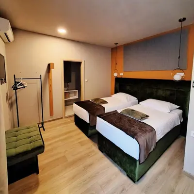 a hotel room with two beds and a chair at Boutique Hotel St Georgije in Banja Luka
