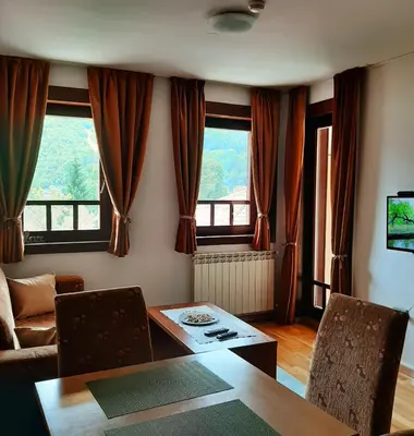 a living room with a table and two windows at Relax Apartman sa garažom in Fojnica