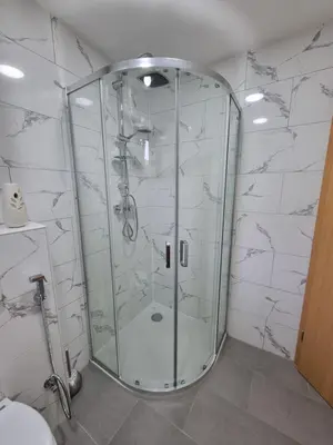 a glass shower in a bathroom with white tiles at Private Riverside House on the Una River with Private Beach in Kulen Vakuf