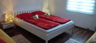a bedroom with a bed with red comforter and two gold awards at Apartment Dil in Kulen Vakuf