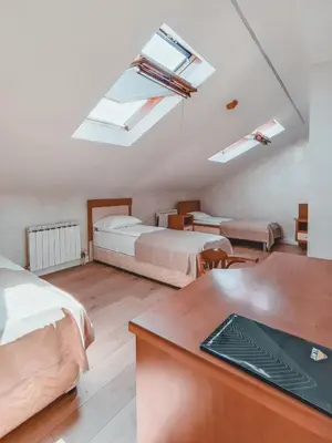 a bedroom with two beds and a desk and skylights at Motel West in Zenica