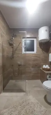 a bathroom with a shower with a toilet and a television at Apartman EXCLUZIV in Prijedor
