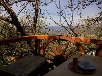 a table with a cup of coffee and a wooden wheel at Bungalows Old Town in Visoko