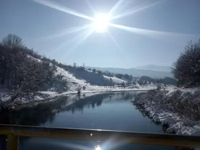 a river covered in snow with the sun in the sky at Apartment Stanic in Šipovo