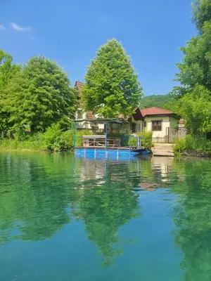a house on a river with a house in the background at Villa Happy dreams in Bihać