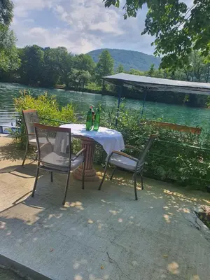 a table with two green bottles on it next to a lake at Villa Happy dreams in Bihać