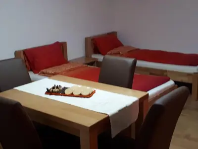 a room with a table with chairs and two beds at Apartmani Tajra in Visoko