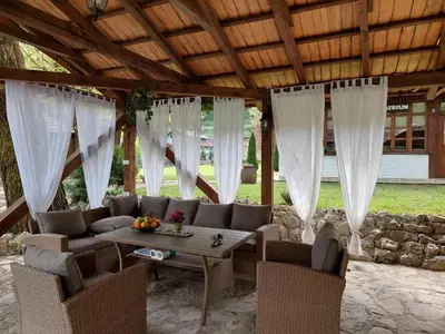 a pavilion with a table and chairs under a wooden ceiling at ATRIUM Holiday home in Bihać