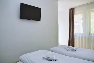 a room with two beds and a flat screen tv on the wall at Guesthouse Marivo in Jajce