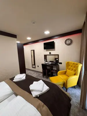 a hotel room with a bed and a yellow chair at Villa Aroma 2 in Orašje