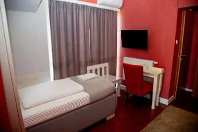 a bedroom with a bed and a desk with a red wall at So&sol boutique Hotel, Tuzla in Tuzla