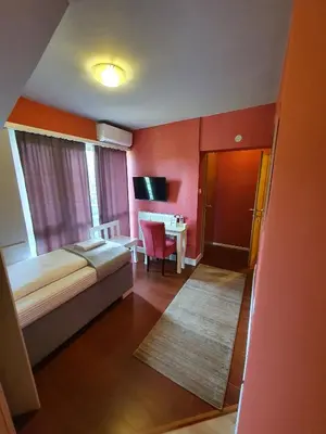 a bedroom with a bed and a table with a chair at So&sol boutique Hotel, Tuzla in Tuzla