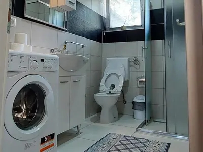 a bathroom with a washing machine and a toilet at Apartments Window in Bihać
