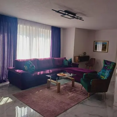 a living room with a purple couch and a table at Family estate Hadžalova avlija in Bihać