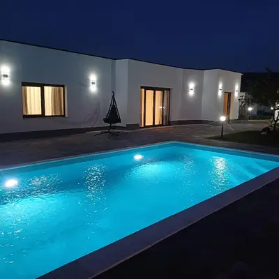 a swimming pool in front of a house at night at Family estate Hadžalova avlija in Bihać