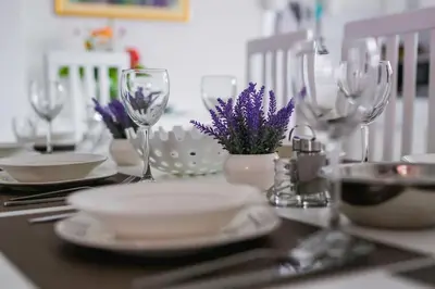 a table with plates and wine glasses and purple flowers at LGP Exclusive Apartment in Bihać