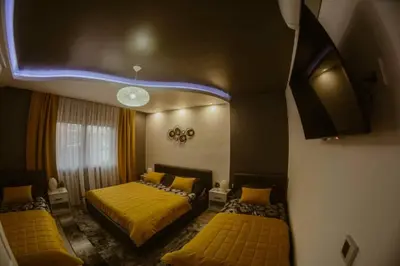 a bedroom with two beds with yellow sheets and a tv at Una Valley Bihać in Bihać