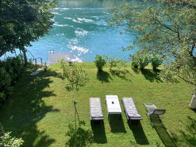 two benches sitting on the grass near the water at Peaceful Oasis - house for rest and relaxation in Bosanska Krupa