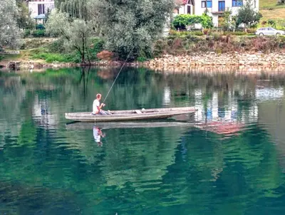 a man in a boat on a lake fishing at Peaceful Oasis - house for rest and relaxation in Bosanska Krupa