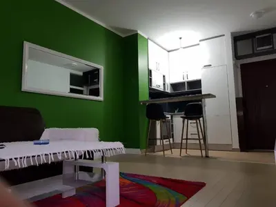 a living room with a green wall and a kitchen at Modern apartment in Banja Luka