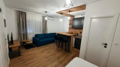 a living room with a blue couch and a kitchen at Apartman Campari in Banja Luka