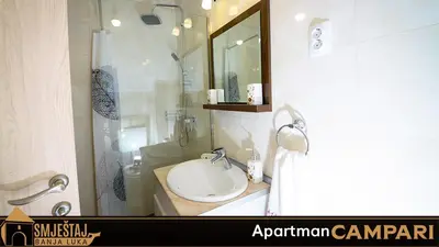 a bathroom with a sink and a shower with a mirror at Apartman Campari in Banja Luka