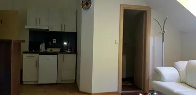 a kitchen with white cabinets and a white couch in a room at Apartman Campari in Banja Luka