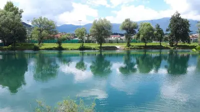 a lake with trees and mountains in the background at Apartment Una Laguna in Bihać