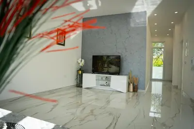 a living room with a television and a marble floor at Apartment Una Laguna in Bihać