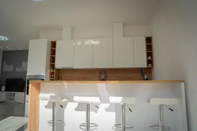 a kitchen with white cabinets and bar stools at Apartment Una Laguna in Bihać