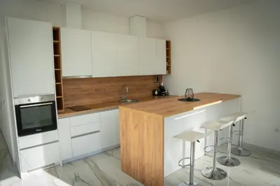 a kitchen with white cabinets and a sink and stools at Apartment Una Laguna in Bihać