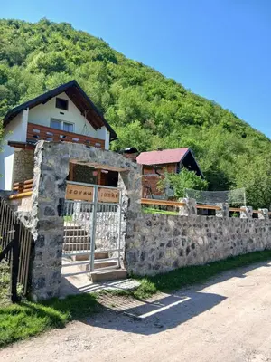 a house with a stone fence in front of a hill at Jovan in Šipovo